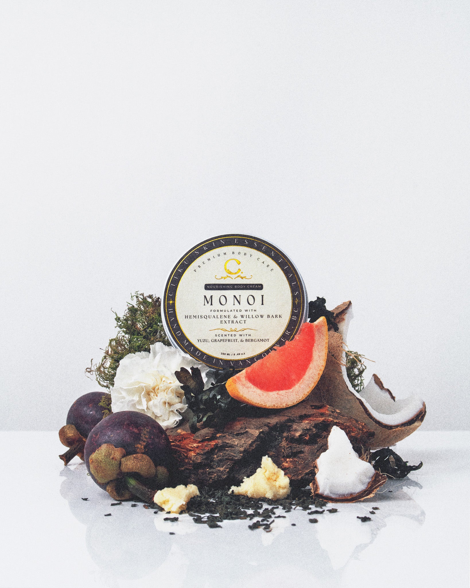 Ciiku Skin Essentials Monoi Body Cream jar surrounded by coconut, grapefruit, and botanicals